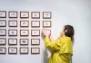 W jaki sposób galerie uczelniane wspierają młodych twórców Studentka wiesza serię małych obrazów w białej galerii.